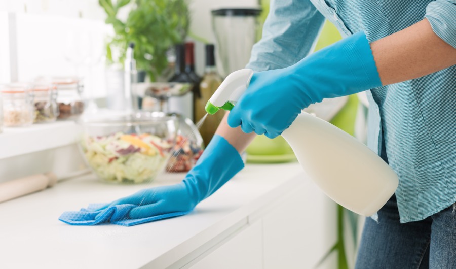 Mujer limpiando y puliendo la encimera de la cocina con un detergente en spray, concepto de limpieza e higiene